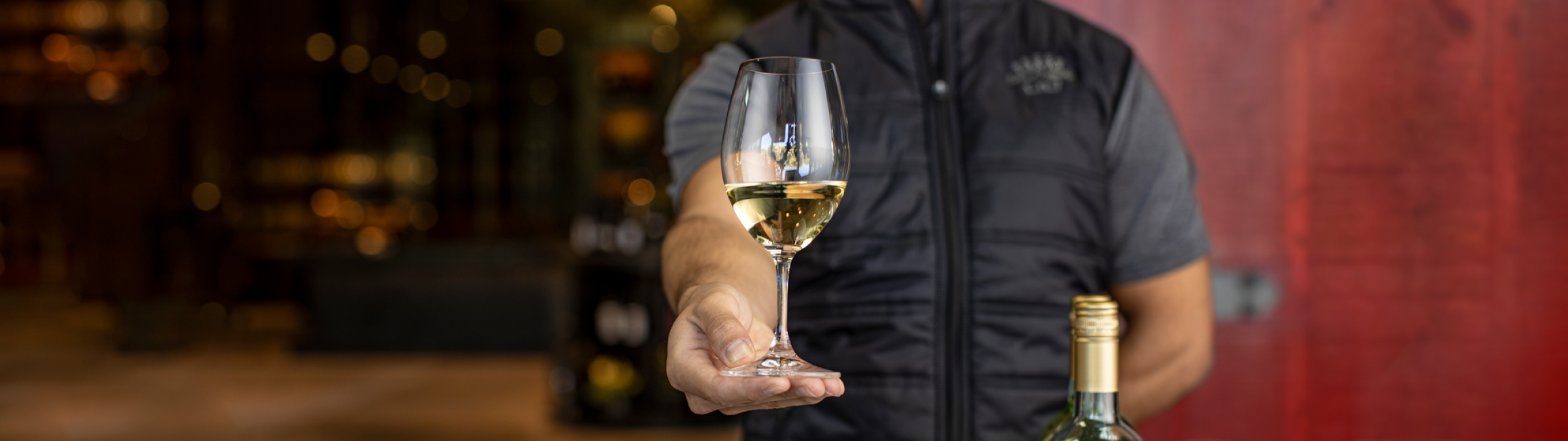 Man holding out a glass of white wine.